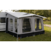 Witte caravan met grijs voortentluifel en grote gaasramen, op gras met bomen op de achtergrond