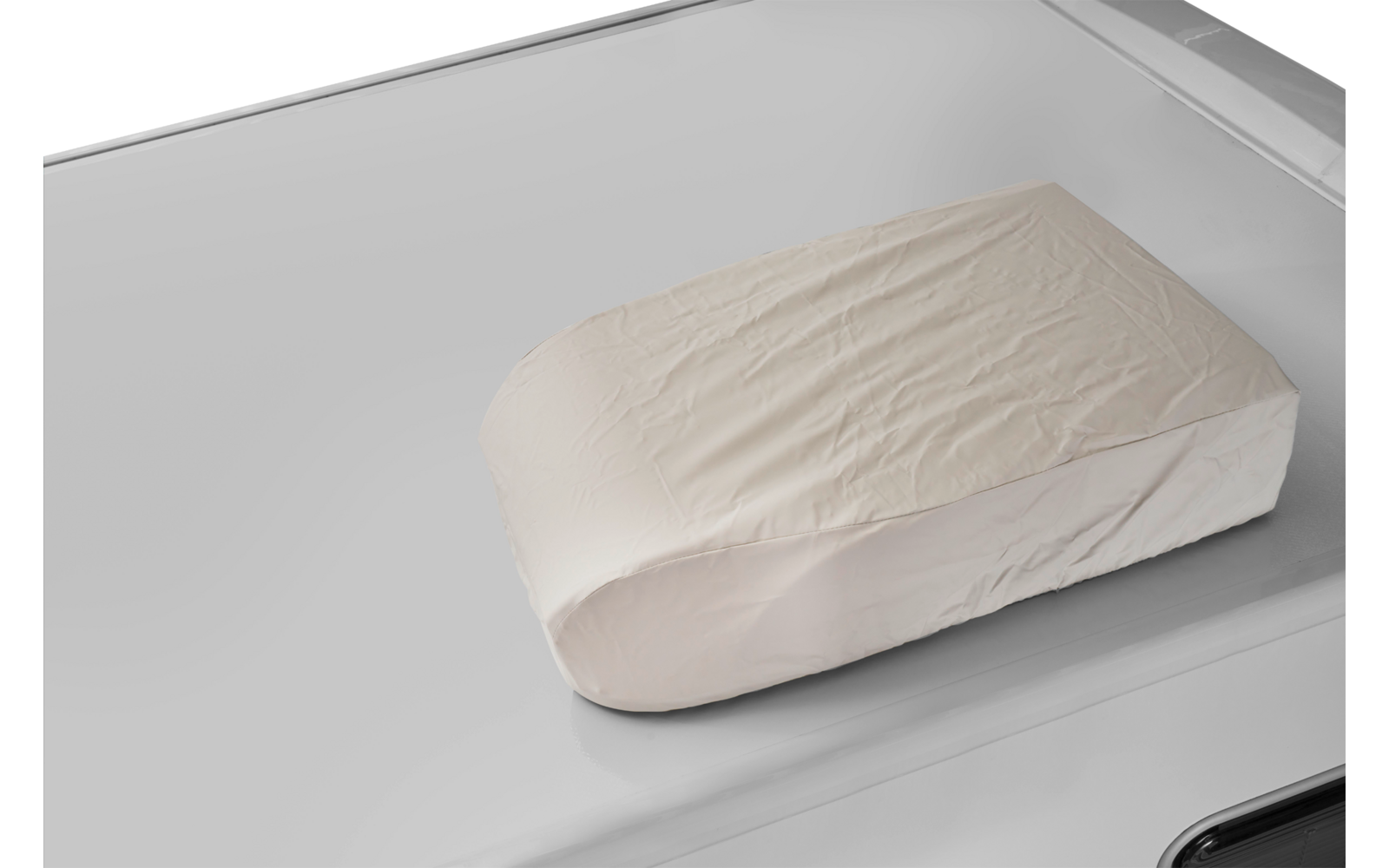 Funda rectangular de tela beige claro con arrugas sobre una superficie brillante gris plateada