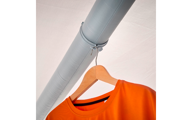 Oranges T‑Shirt auf einem Holzkleiderbügel, der mit einer Schnur an einem grauen Rohr hängt