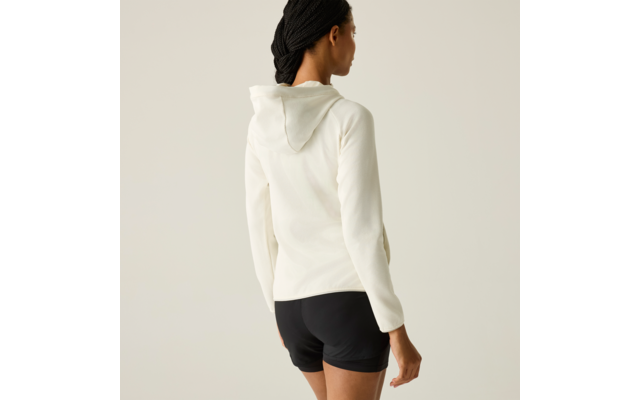 Rückansicht einer stehenden Person mit dunklen, geflochtenen Haaren, weißem Kapuzenpullover und schwarzen Shorts vor hellem Hintergrund