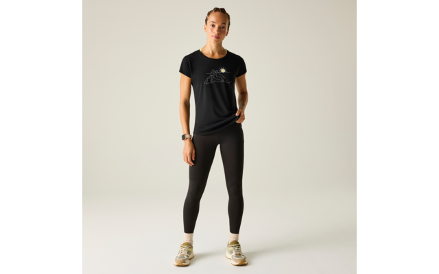 Frau steht frontal, trägt schwarzes T‑Shirt mit kleiner weißer Grafik, schwarze Leggings, weiße Socken und beige Sneaker; Haare zu einem Dutt gebunden; Smartwatch am linken Handgelenk