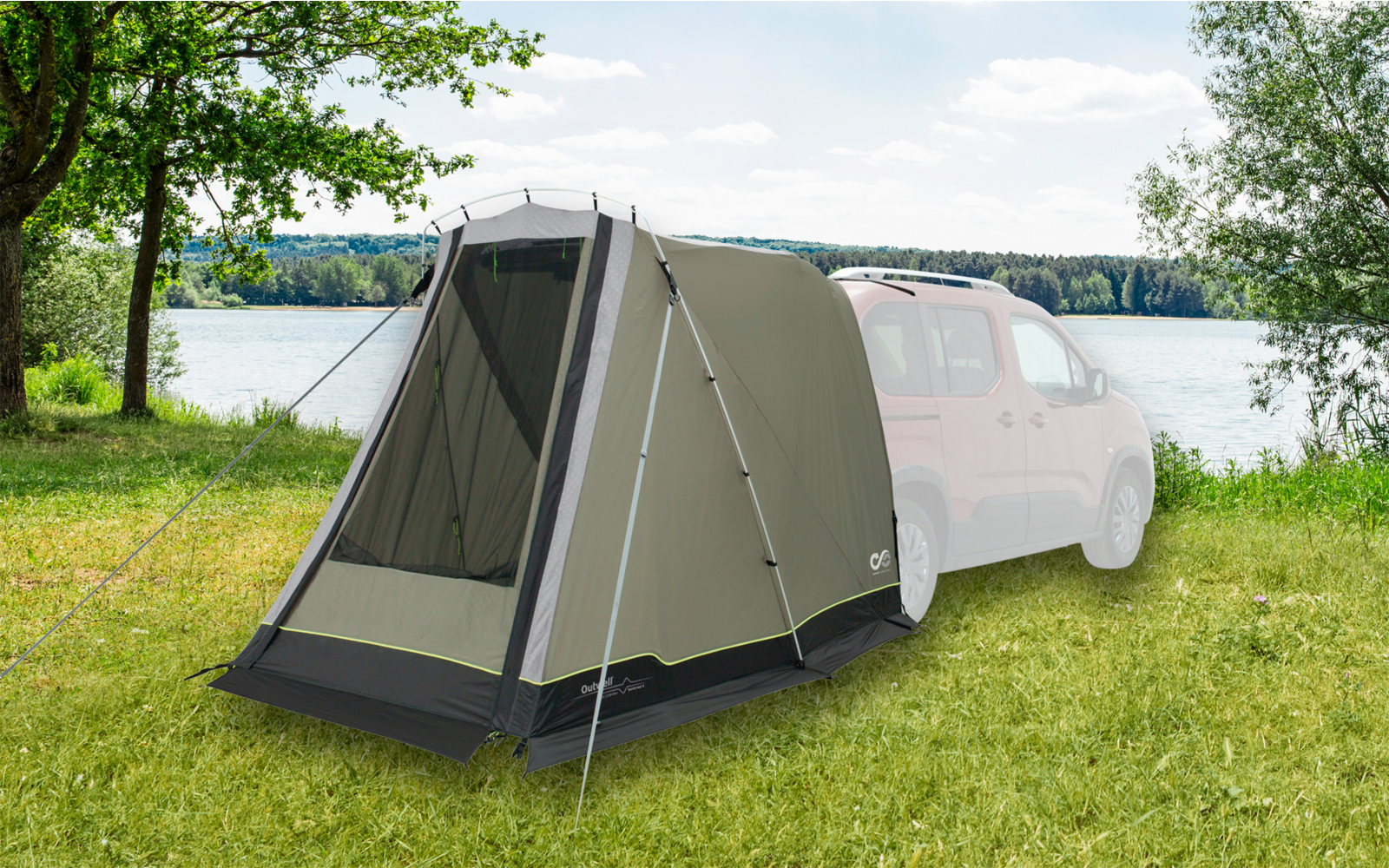 Vorzelt an einem weißen Camper auf einer Wiese neben einem See