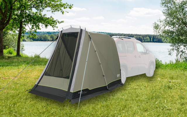 Vorzelt an einem weißen Camper auf einer Wiese neben einem See