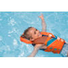 Kind mit geflochtenen Haaren treibt auf dem Rücken in einem blauen Schwimmbecken, trägt eine orangefarbene Schwimmweste, lächelnd, Arme ausgestreckt