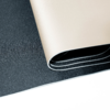 Feuille beige texturée enroulée sur une surface noire texturée, fond blanc