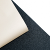 Feuille beige texturée avec coin plié sur surface noire granuleuse, zone blanche en haut à droite
