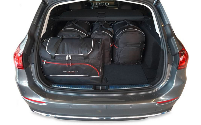 Coffre ouvert d'une voiture grise avec trois sacs de voyage noirs