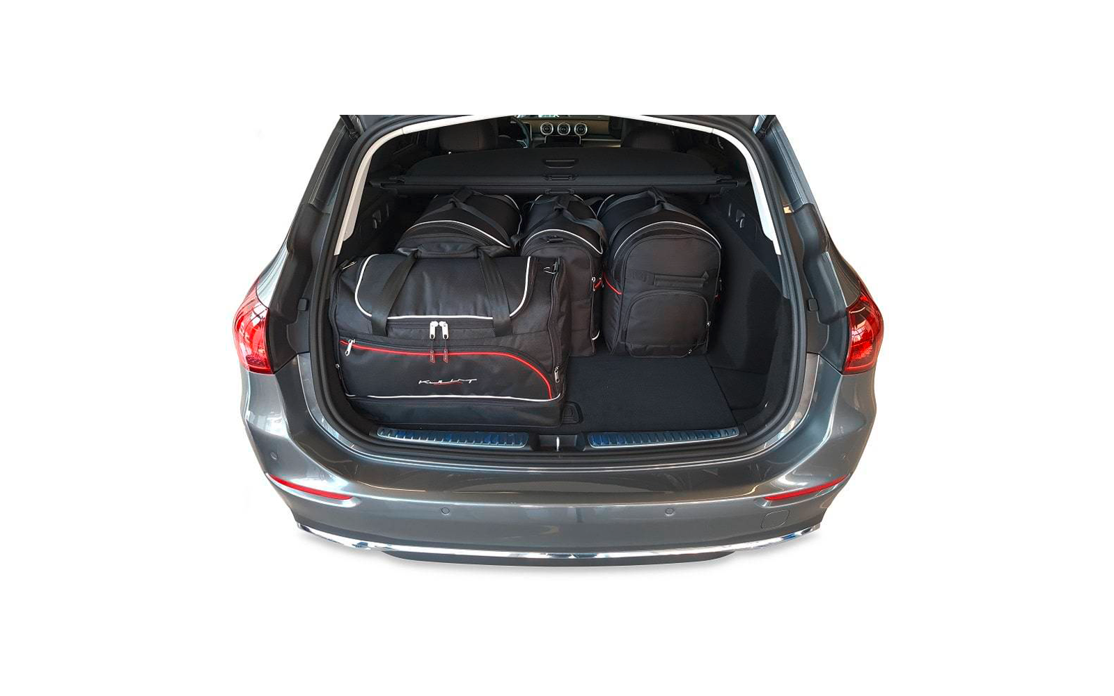 Coffre ouvert d'une voiture grise avec trois sacs de voyage noirs