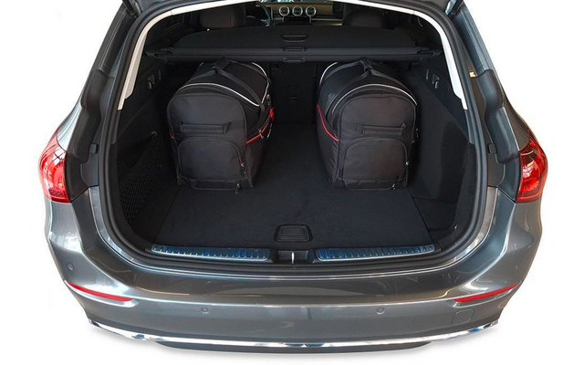Coffre ouvert d'une voiture grise avec deux sacs de voyage noirs côte à côte