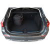 Coffre ouvert d'une voiture grise, sac noir à gauche, tapis sombre, cache-bagages rétractable visible
