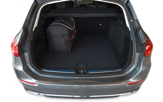 Coffre ouvert d'une voiture grise, sac noir à gauche, tapis sombre, cache-bagages rétractable visible