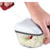 Deux mains utilisent un hachoir manuel avec couvercle blanc ; le bol transparent contient de petits morceaux blancs hachés ; une main tire sur une poignée rouge à cordon