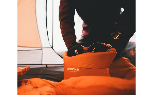 Persoon zit in tent en pakt oranje tas uit