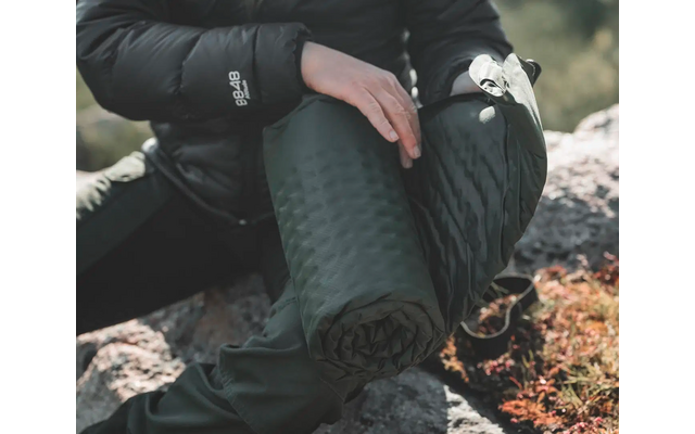 Person hält eine zusammengerollte Isomatte mit beiden Händen