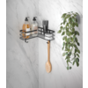 Schwarzes Wandregal mit Flaschen, Gläsern, einem Holzlöffel und hängender grüner Pflanze vor weiß marmorierter Wand