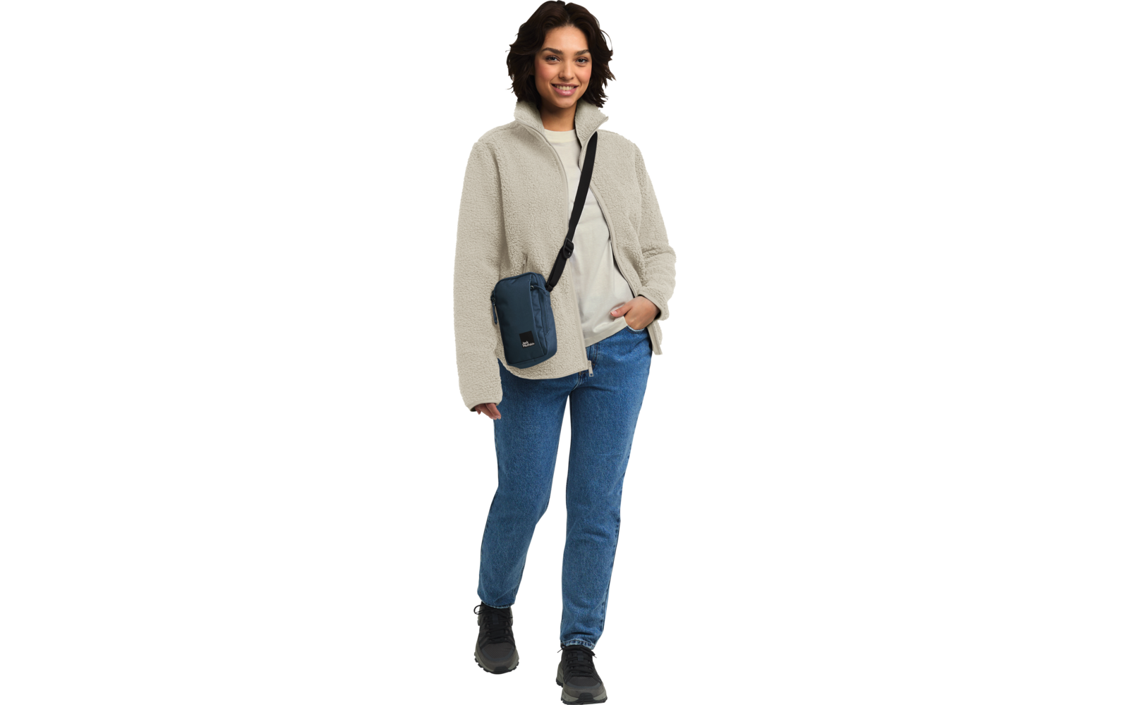 Frau steht, trägt helle Jacke, blaue Jeans und schwarze Tasche über der Schulter