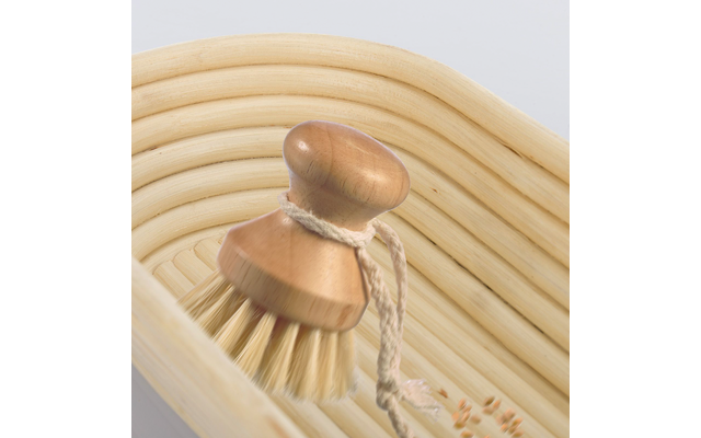 Ronde houten borstel met korte steel en haren in een licht geribbeld gevlochten mandje; borstel heeft een koordje, een paar verspreide zaden ernaast