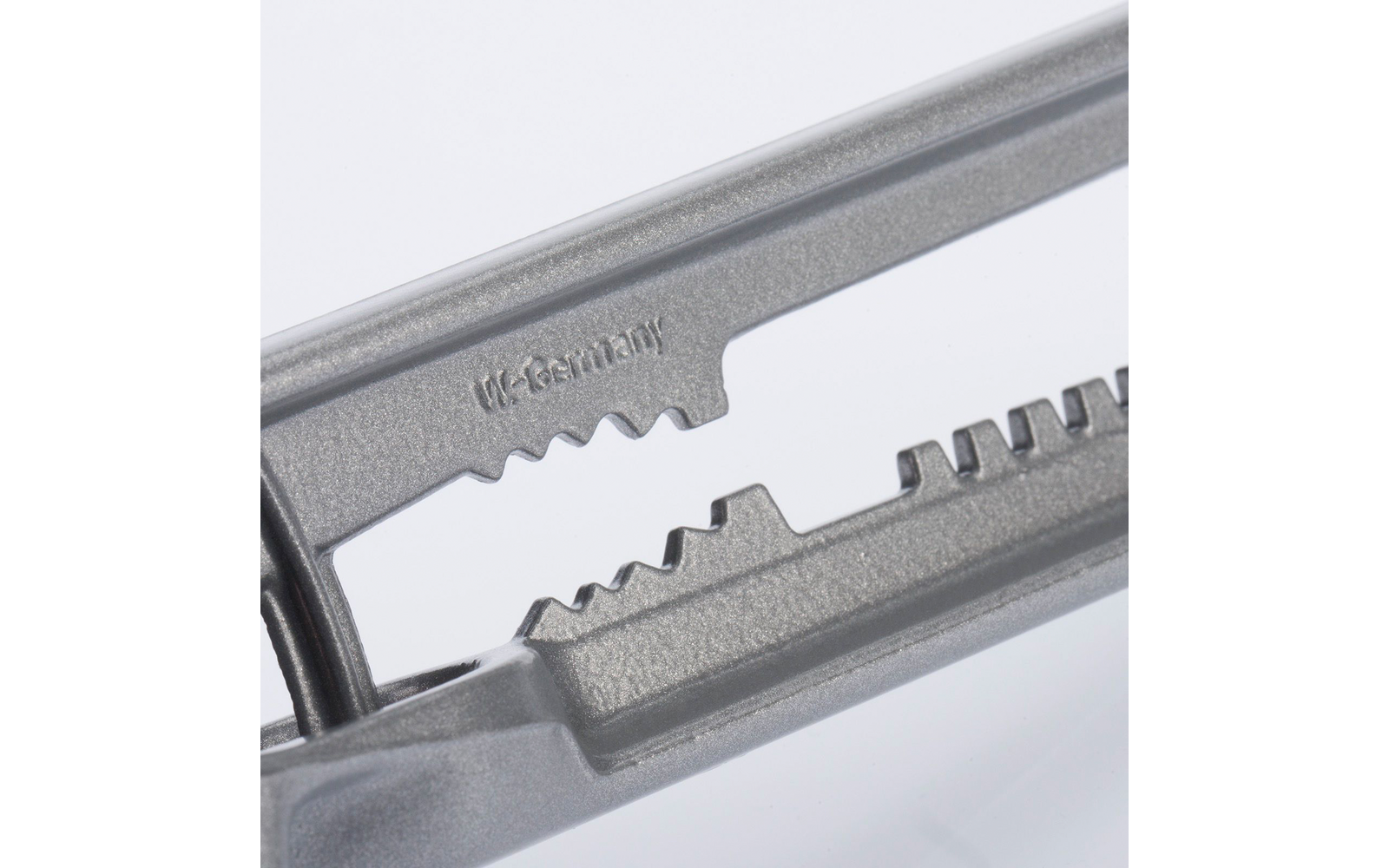 Close-up van twee in elkaar grijpende getande metalen geleiders met de geperste tekst 'UK-Germany' op een lichte achtergrond