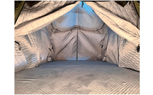 Intérieur d'une tente avec doublure matelassée argentée, entrée triangulaire ouverte, couture centrale et sol matelassé