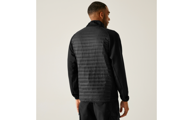 Man van achteren in een zwarte gewatteerde jas en zwarte broek voor een lichte achtergrond