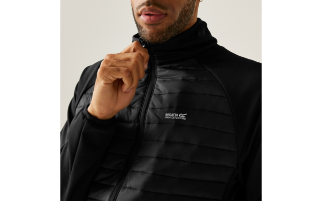 Close-up van het bovenlichaam van een persoon in een zwarte doorgestikte jas met rits, hand bij de kraag, 'Regatta Great Outdoors' logo zichtbaar op de borst