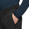 Bovenlichaam van een persoon met een donkerblauw shirt met lange mouwen, hand in de ritszak van een zwarte broek