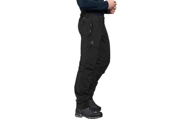 Zijaanzicht van het onderlichaam van een persoon met een donkerblauw longsleeve, zwarte outdoorbroek met ritszakken en driehoekig logo, en zwarte wandelschoenen op witte achtergrond