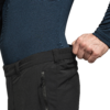 Bovenlichaam van een persoon in een donkerblauw shirt met lange mouwen, hand trekt de tailleband van een zwarte broek zijwaarts naar buiten
