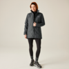 Femme portant une veste grise, des leggings noirs et des chaussures noires, debout devant un fond beige