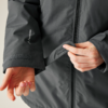 Mains fermant une fermeture éclair sur une veste grise