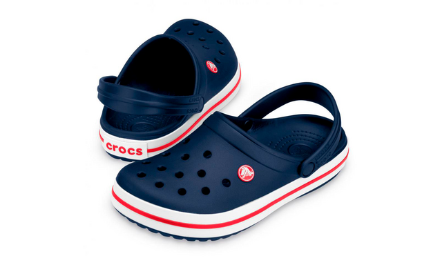Dunkelblaues Paar Clogs mit Belüftungsöffnungen, verstellbaren Fersenriemen, weißer Sohle mit rotem Streifen, Markenaufdruck an der Ferse und rundem Logo an der Außenseite