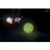 Leuchtender grüner Ball auf dunklem Boden bei Nacht mit unscharfem Baum im Hintergrund