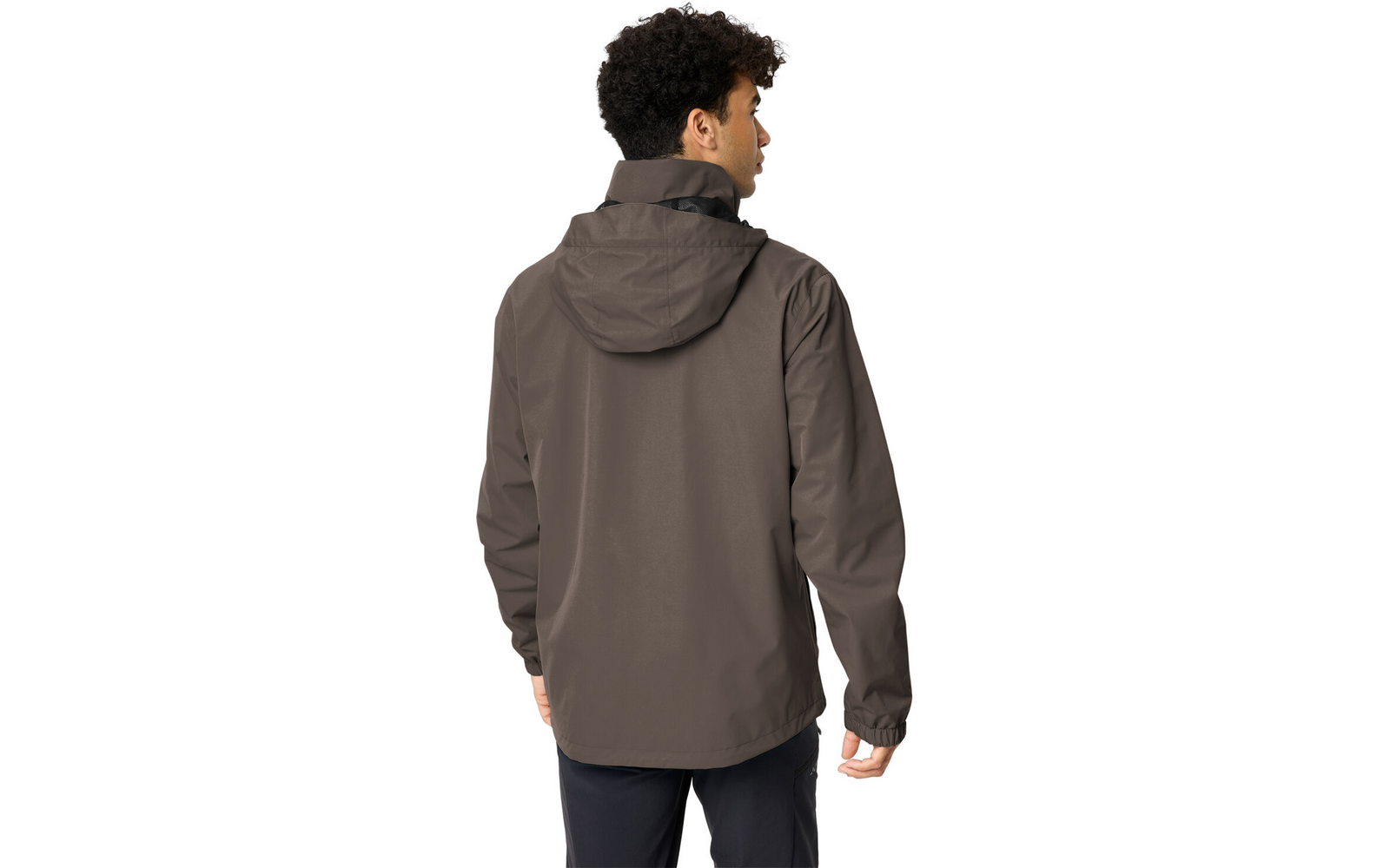 Mann von hinten, trägt graubraune Kapuzenjacke und dunkle Hose, Kopf nach rechts gedreht, lockiges dunkles Haar sichtbar