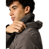Person im Profil mit kurzen, dunklen, lockigen Haaren, die mit der Hand die Kapuze einer dunkelgrauen Jacke hochzieht