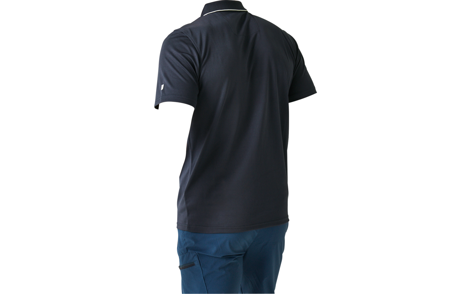 Person von hinten, trägt dunkelblaues Poloshirt und blaue Hose, schaut über die linke Schulter, heller einfarbiger Hintergrund