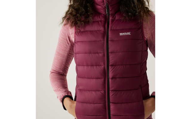 Frau trägt eine dunkelrote gesteppte Daunenweste über einem langen rosa Shirt