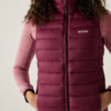 Frau trägt eine dunkelrote gesteppte Daunenweste über einem langen rosa Shirt
