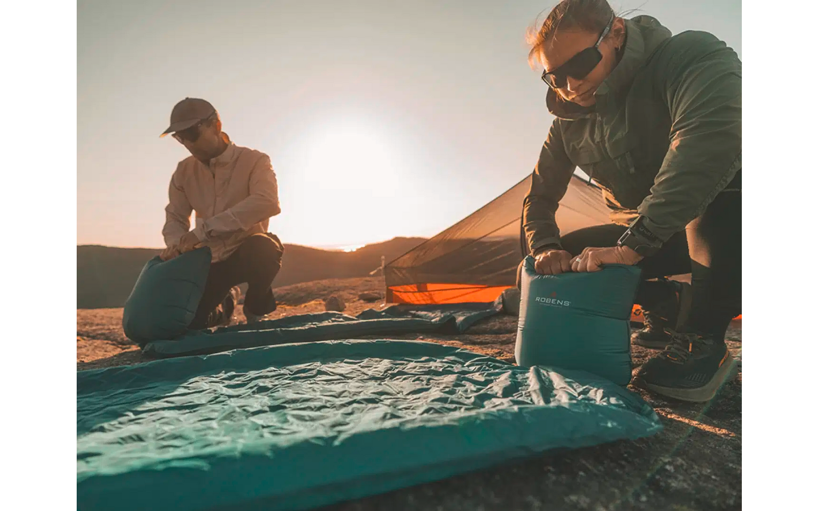 Twee mensen bereiden een zeilboot voor bij zonsondergang