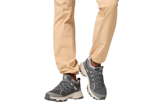 Jambes d'une personne portant un pantalon beige et des chaussures de sport grises