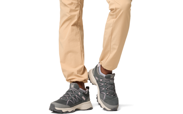 Beine einer Person mit beige Hose und grauen Sportschuhen