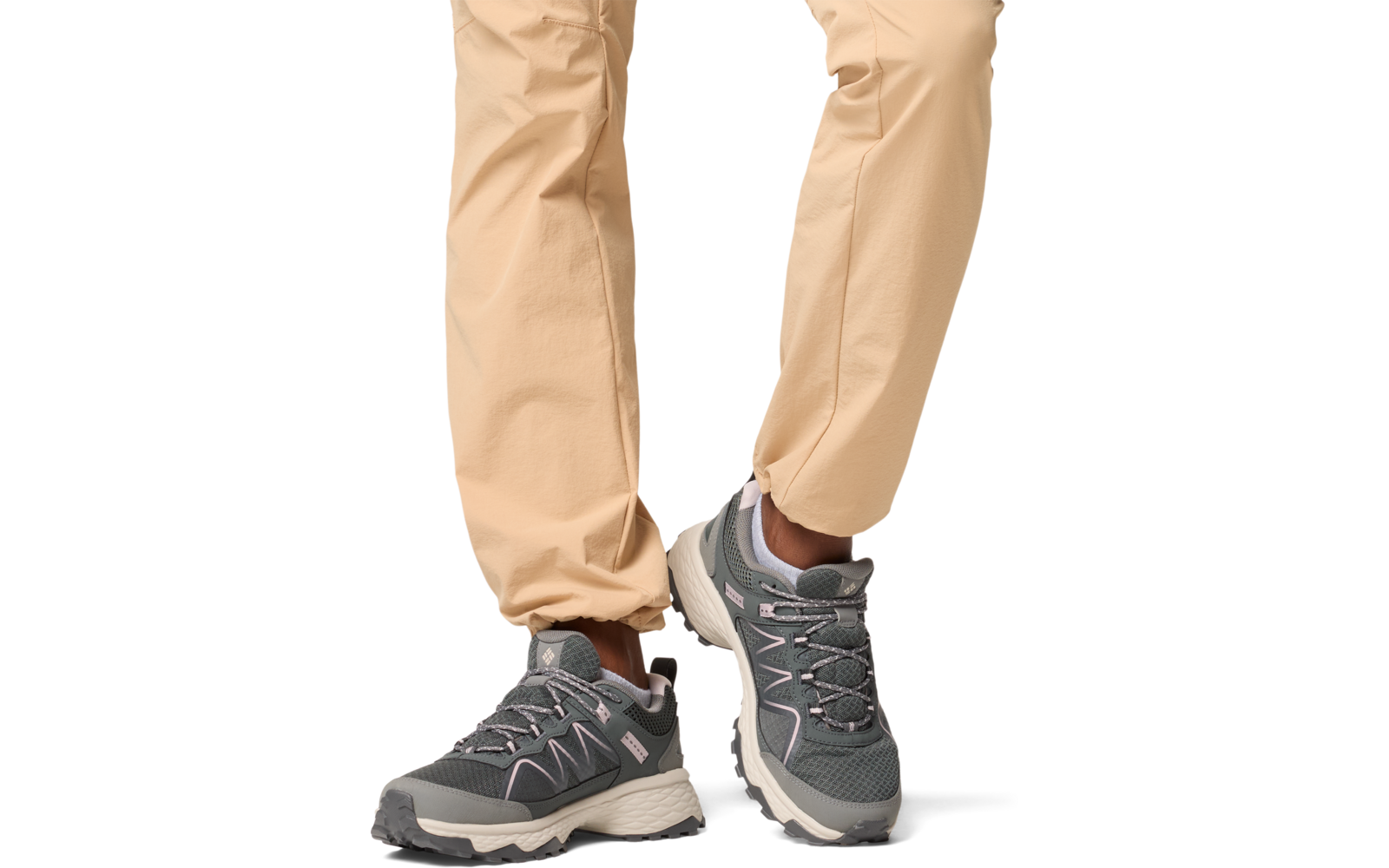 Beine einer Person mit beige Hose und grauen Sportschuhen