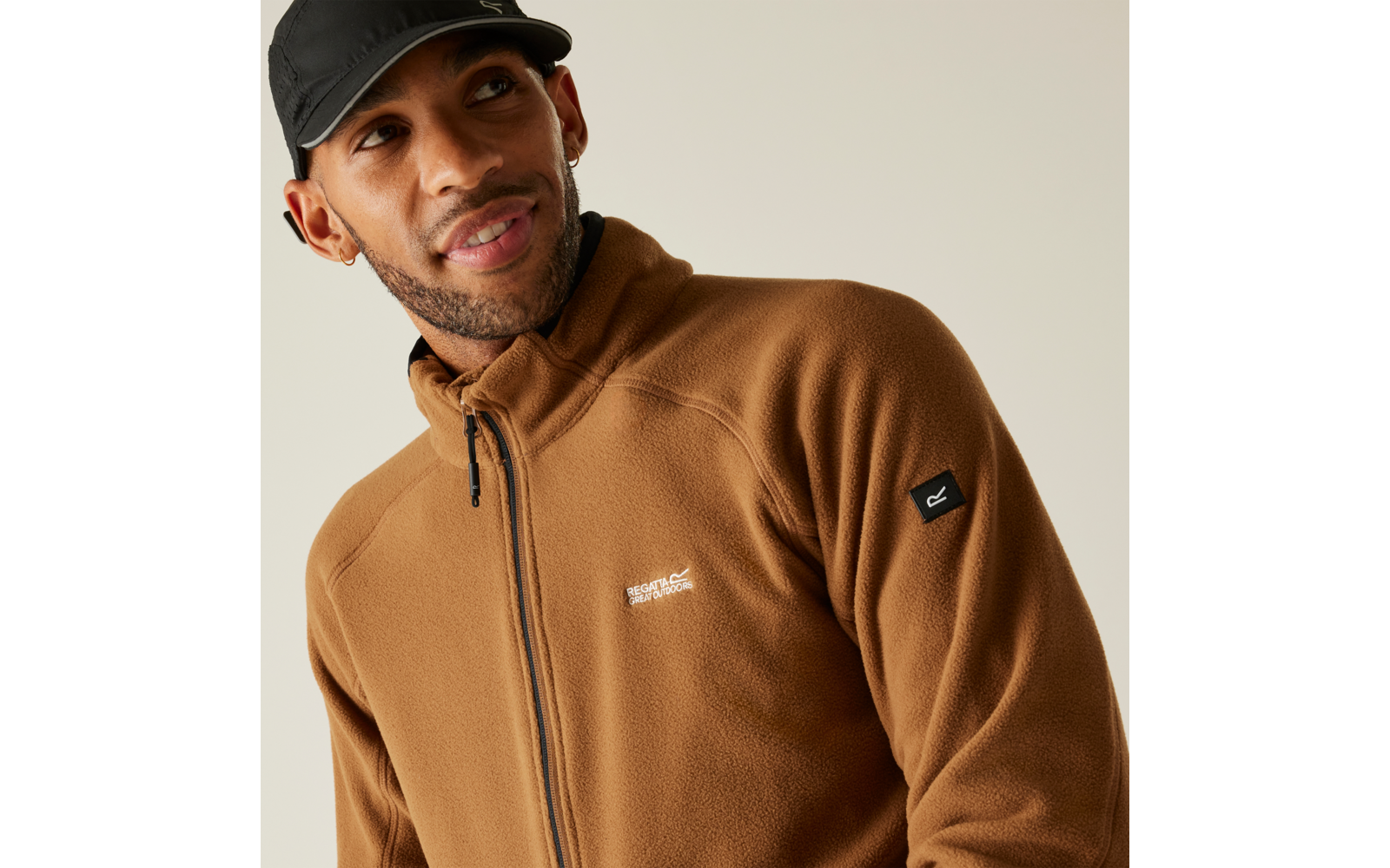 Mann trägt braune Jacke und schwarze Kappe, schaut nach links