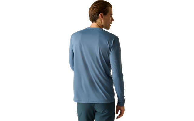 Person von hinten, trägt blaues langärmeliges Shirt und dunkle Hose, steht vor hellem einfarbigem Hintergrund, Kopf leicht nach rechts gedreht