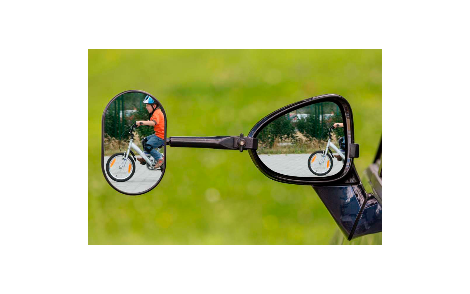 Blick in die Rückspiegel eines Fahrzeugs, in denen ein Radfahrer mit Helm auf einem Fahrrad sichtbar ist