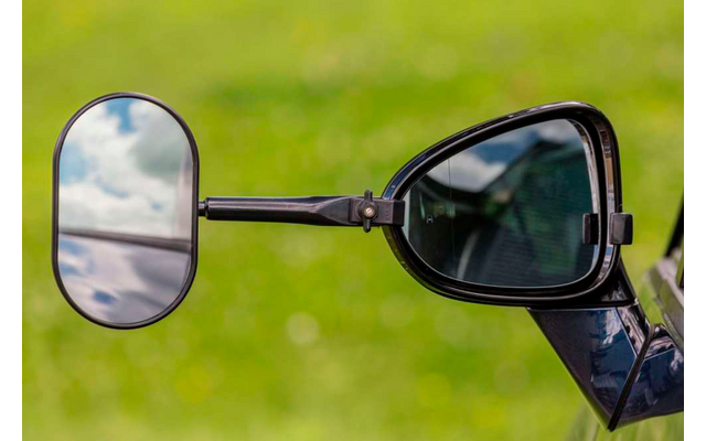 Rückspiegel und Sonnenbrille an einem Fahrzeug vor grünem Hintergrund