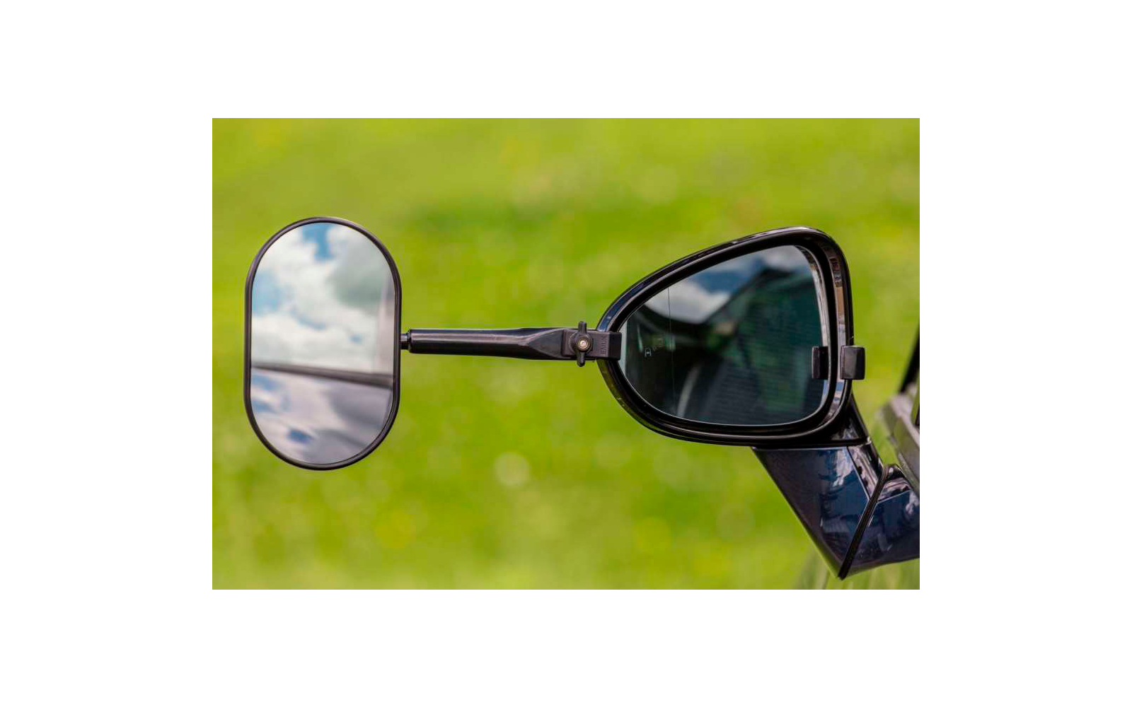 Rückspiegel und Sonnenbrille an einem Fahrzeug vor grünem Hintergrund
