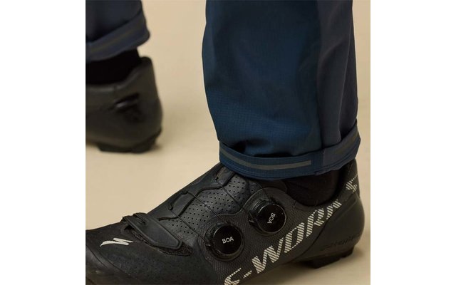 Nahaufnahme eines Fußes in schwarzem Fahrradschuh mit zwei runden Verschlüssen und dunkelblauer Hose