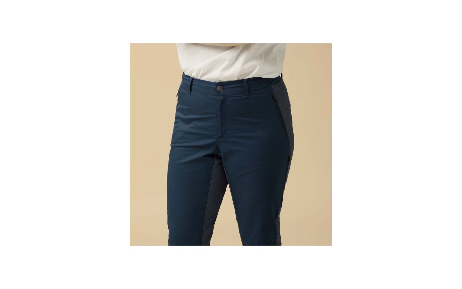 Hüft- und Oberschenkelbereich in dunkelblauen Hosen und weißem Hemd vor beigem Hintergrund