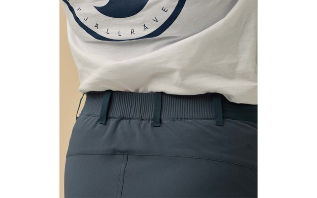 Unterer Rückenbereich mit weißem T‑Shirtsaum und rundem dunkelblauem Aufdruck, dunkelblaue Hose mit geripptem elastischem Bund und Gürtelschlaufen