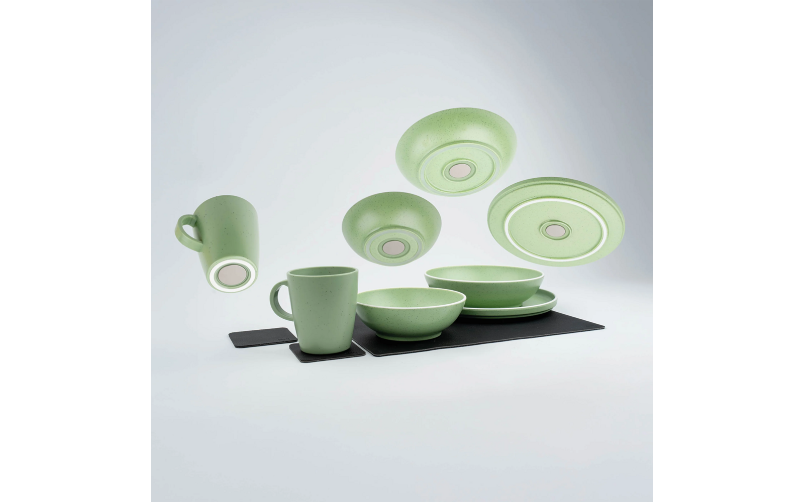 Groen servies set met kopjes, kommen en borden op een zwart oppervlak